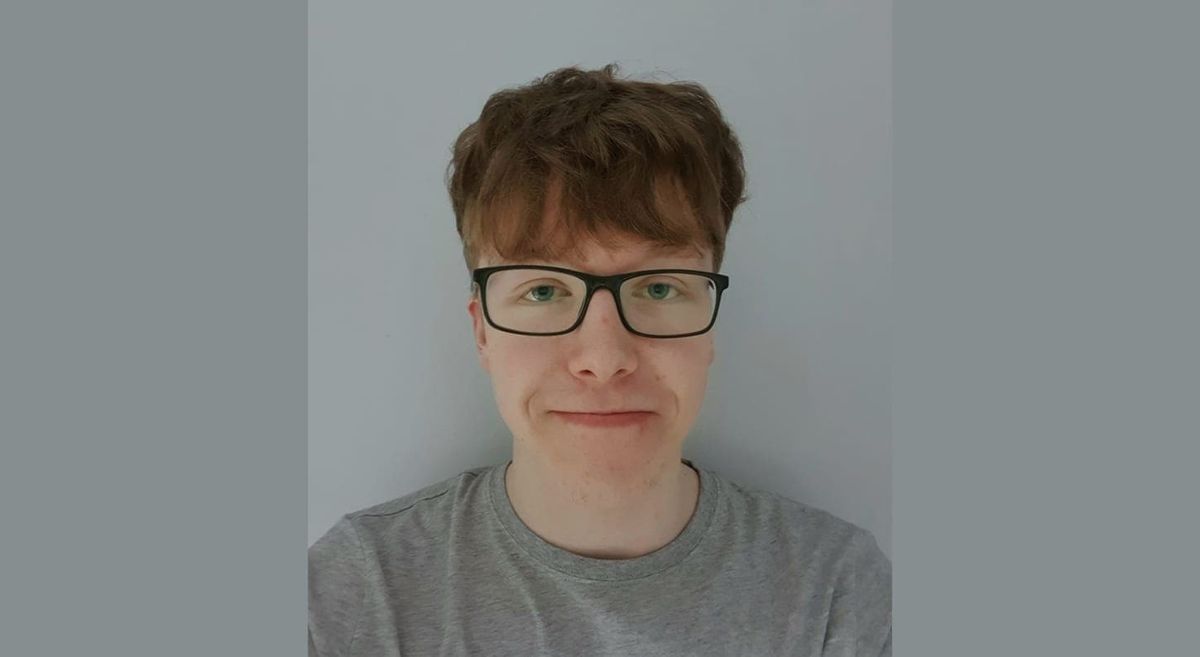 Young male with brown hair, glasses, and grey t-shirt looking at the camera.